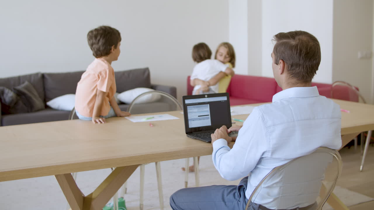 vista de atrás del padre usando en la computadora portátil