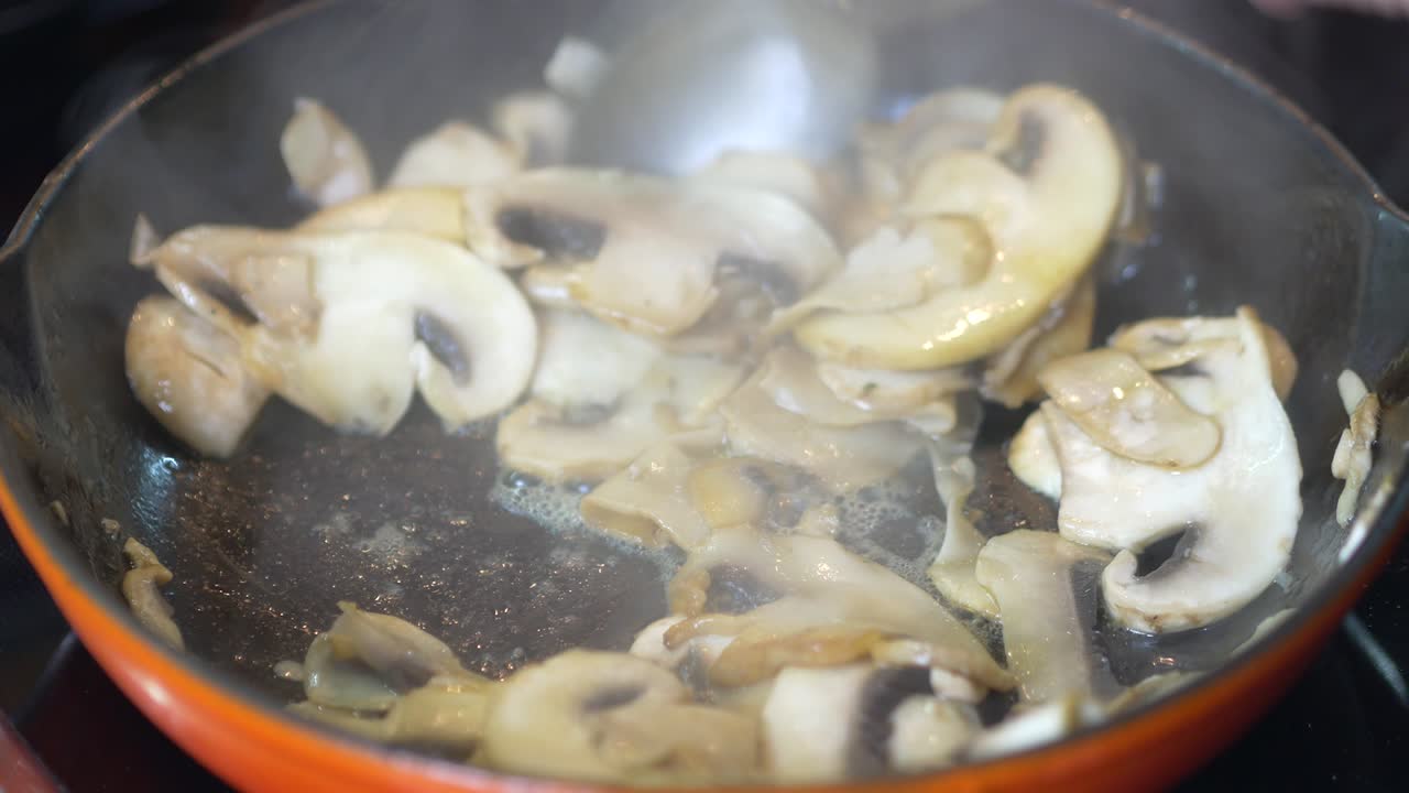 얇게 썬 버섯이 뜨거운 빨간 팬에 튀기고 있습니다.