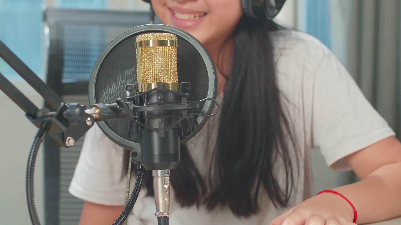 Asian Kid Girl Singing With Microphone During Online Livestream In Podcast Studio