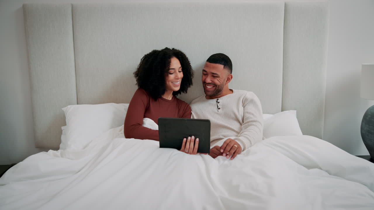 Couple using tablet in bed