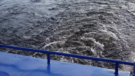 turbulent water wake behind a blue boat