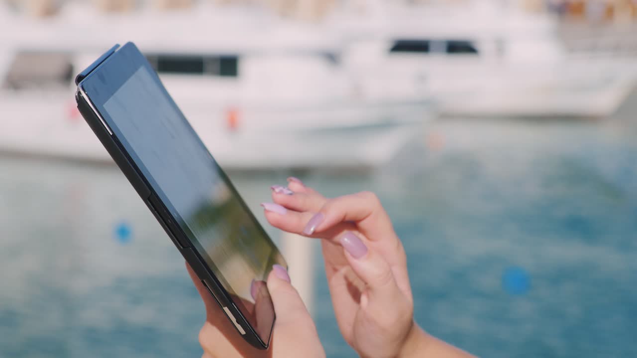 요트 배경에 태블릿이 있는 손