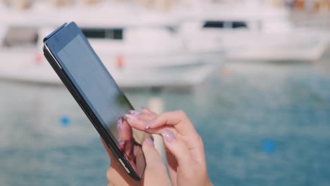 hands with the tablet on the background of yachts