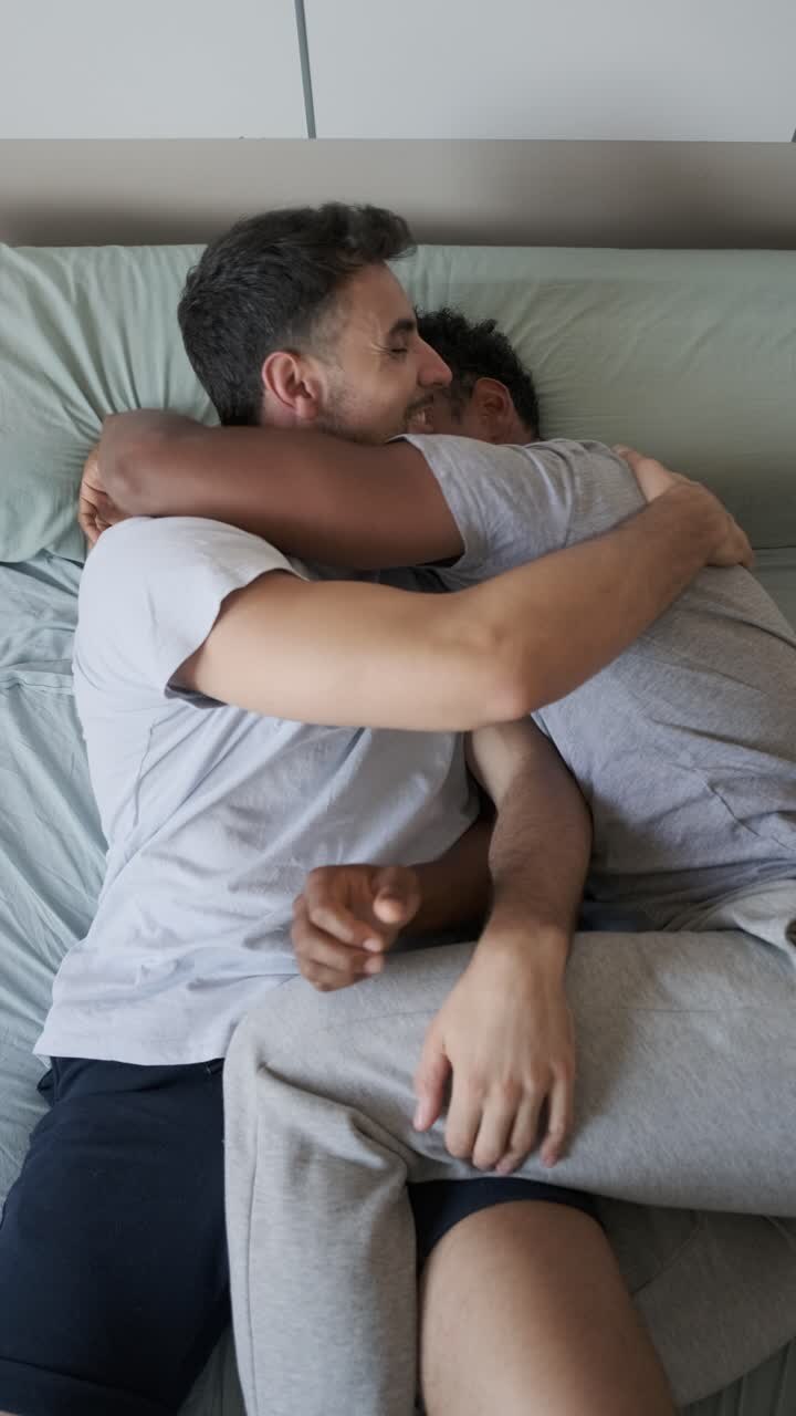 Two men hugging in bed