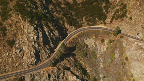 motorway passing through the huge mountain. cars moving by the dangerous road at the edge of rock. aerial view.