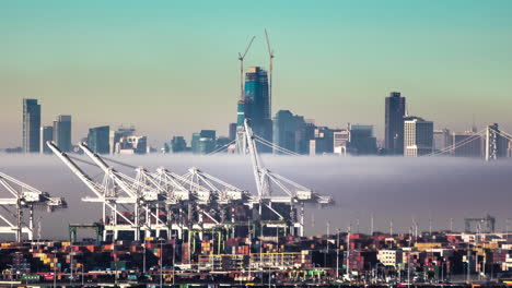 Zeitrafferaufnahme-Von-Niedrigen-Wolken,-Die-über-Den-Containerhafen-Von-San-Francisco-Fliegen,-Mit-Der-Skyline-Im-Hintergrund-Bei-Sonnenaufgang