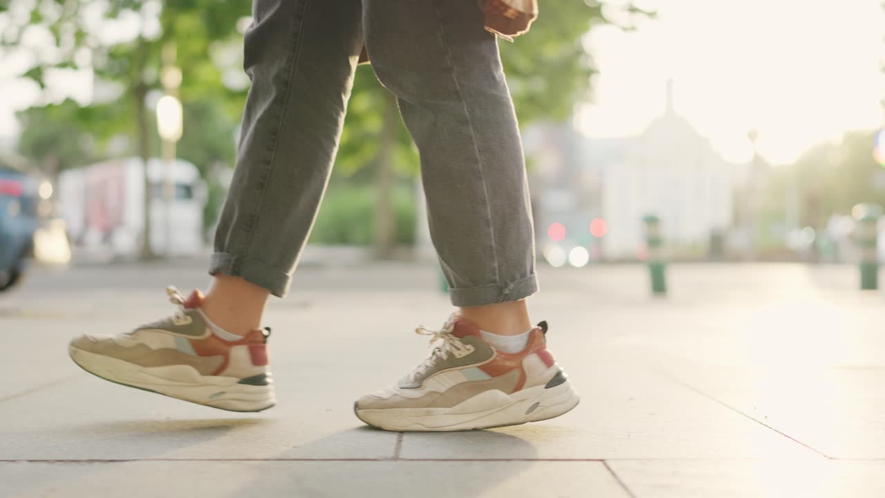 Close-up of person walking on urban sidewalk in sneakers