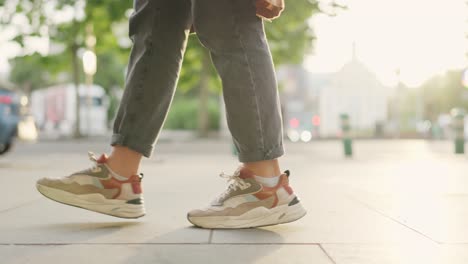 close-up of person walking on urban sidewalk in sneakers