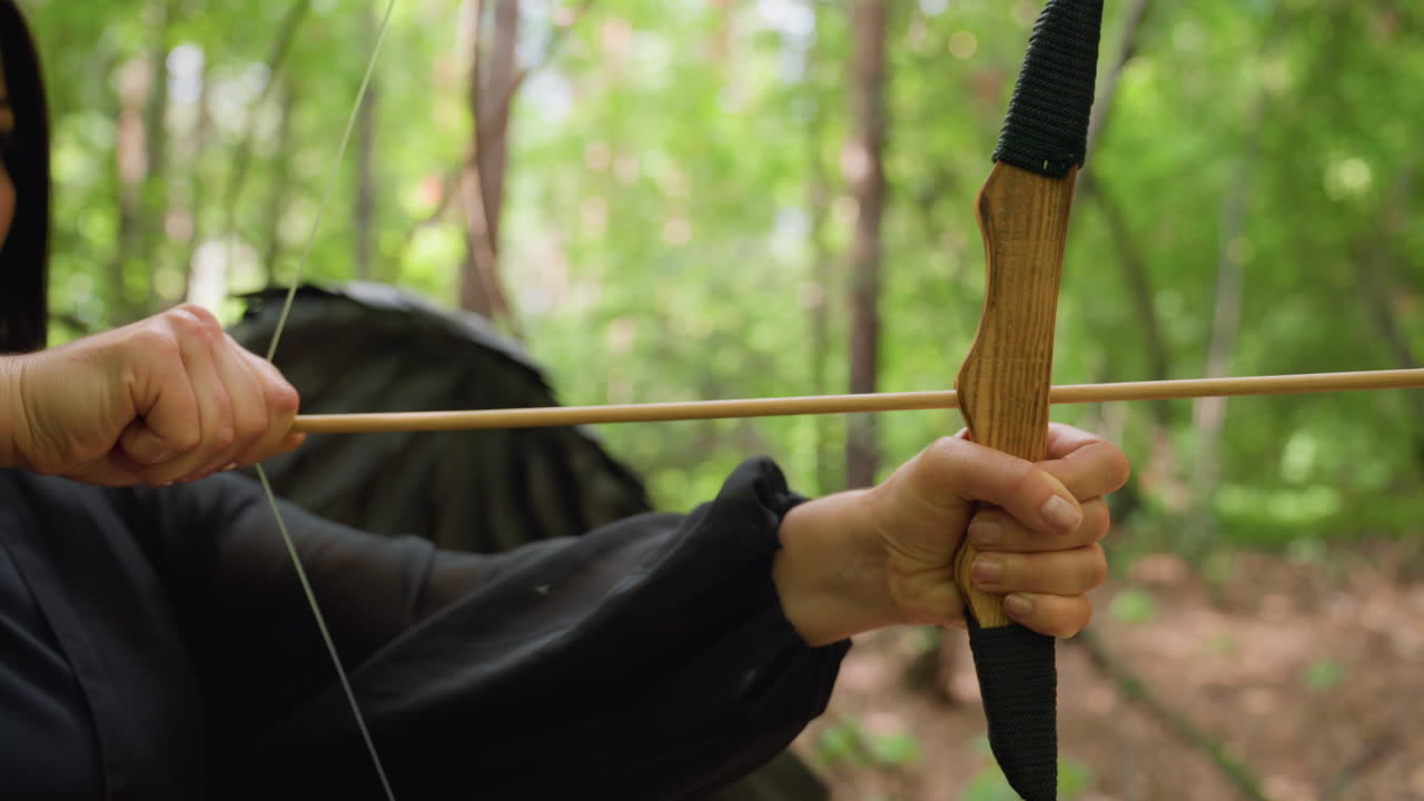 Close up of archer hands pulling wooden bowstring and aiming arrow in forest, sunlight reflecting on natural wood texture, showing focus, strength, and precision in calm mystical atmosphere