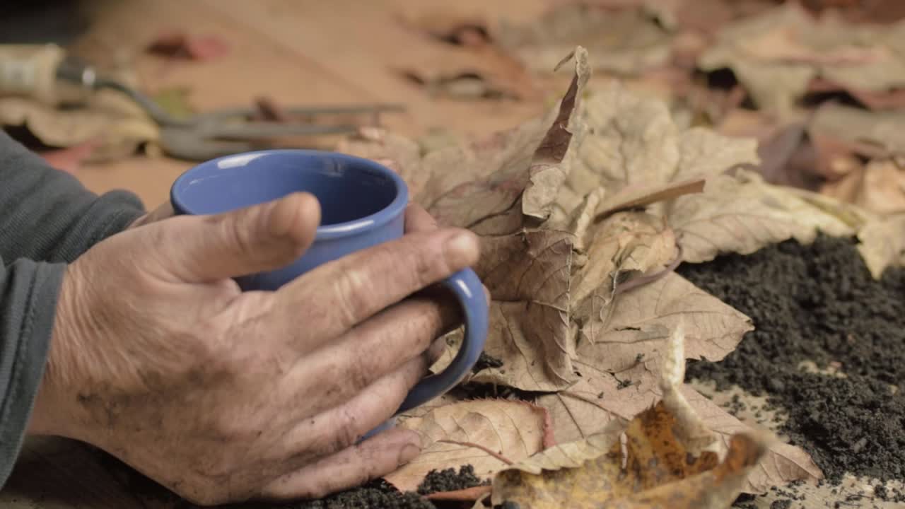 un par de manos frías y sucias calentándose con una bebida caliente
