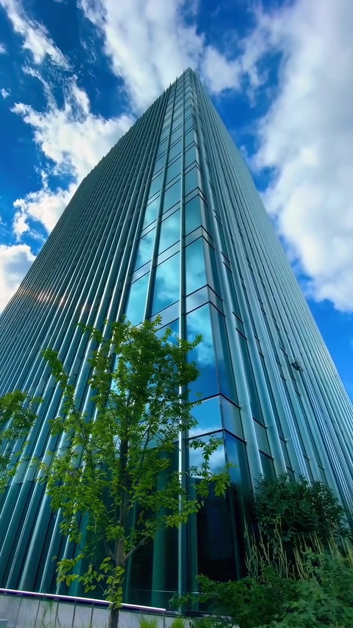Un moderno rascacielos de vidrio que refleja el cielo azul y las nubes
