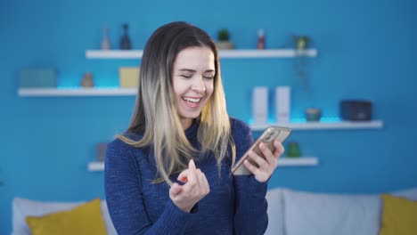 una joven que se alegra leyendo las buenas nuevas por teléfono.