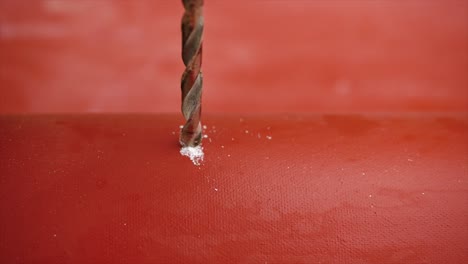 drilling a hole in a red plastic pipe