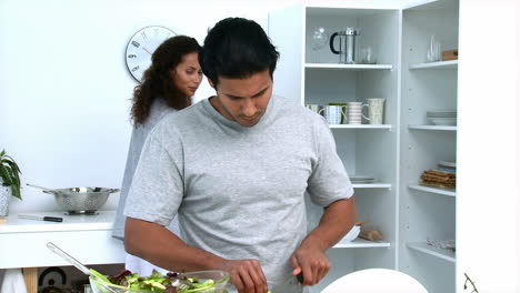 hombre concentrado cortando verduras con su novia