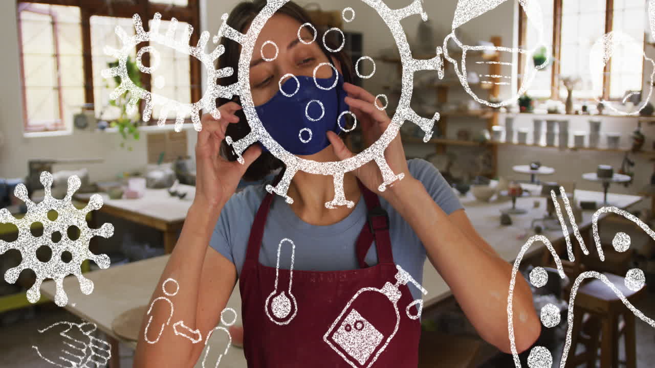 анимация икон вирусов над кавказской женщиной с маской на лице в мастерской