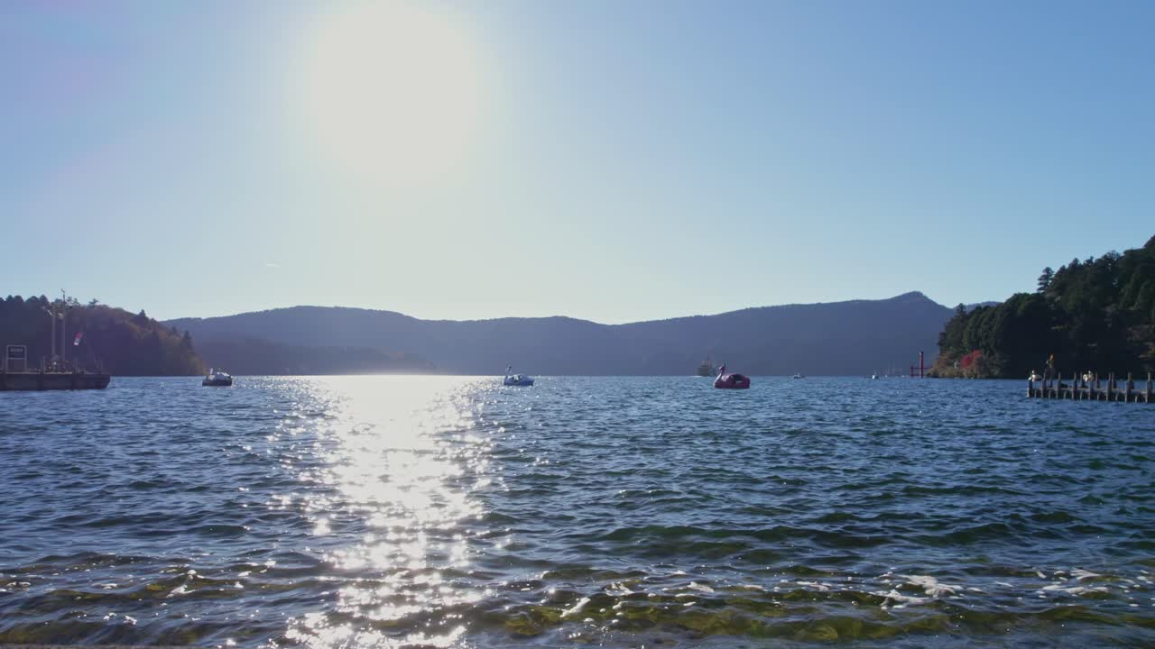 Calm lake view featuring duck boats gliding across Lake Ashi, a popular travel destination near Mount Fuji in Hakone