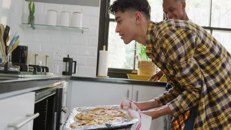 amigos adolescentes felices y diversos preparando pizza en la cocina, cámara lenta