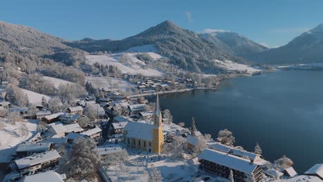 white snow winter landscape at lake schliersee with mountains and dark blue water