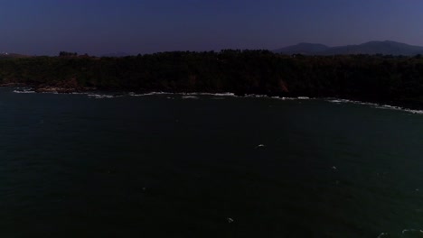 Imágenes-De-Drones-Que-Se-Mueven-Desde-El-Mar-Abierto-Hacia-Una-Playa-Rocosa-Con-Olas-Rompiendo