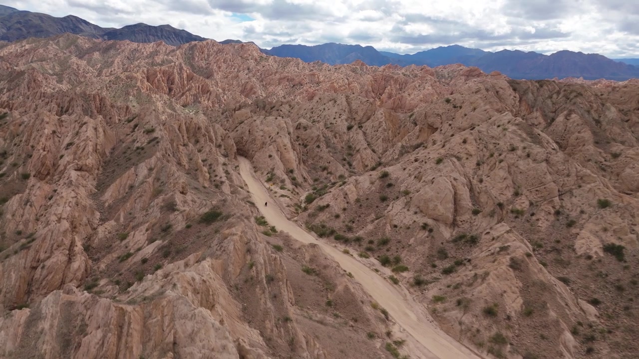 Motorcykel som färdas på slingrande väg genom Quebrada de las Flechas klipplandskap, flygfoto, Salta-regionen, Argentina.