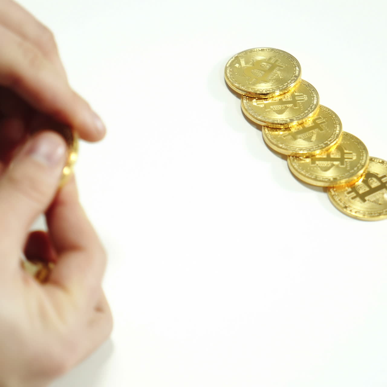 Physical real golden Bitcoin coin in men's hand - virtual crypto currency, financial concept, banknotes of different countries