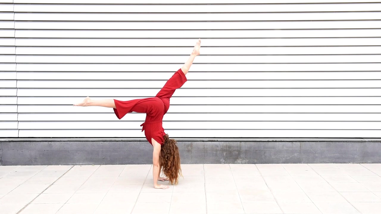 Donna dai capelli rossi e in forma che fa acrobazie fitness in un contesto urbano
