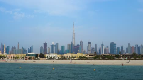 turistas en la costa de la playa de jumeirah con el centro de dubai y burj khalifa en emiratos árabes unidos