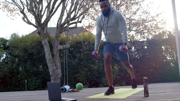 African american man fitness training exercising with weights on deck in sunny garden, slow motion