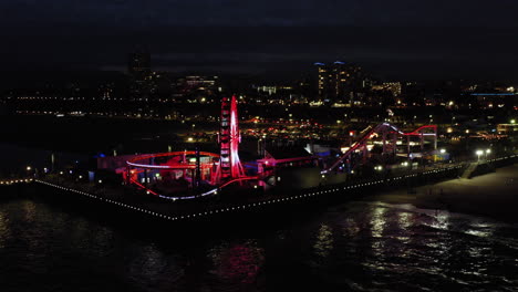 santa monica pier at night with illuminated ferris wheel and roller coaster