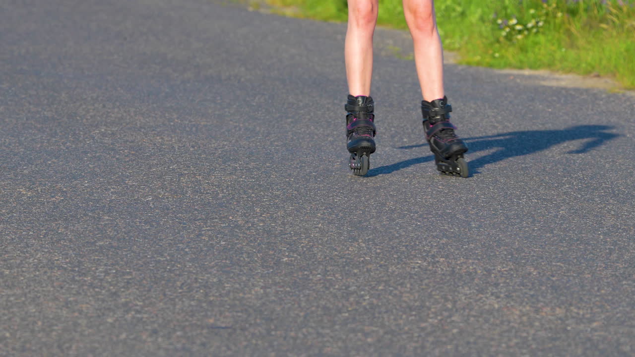 Close-up of a person rollerblading on a paved road, legs and skates in motion