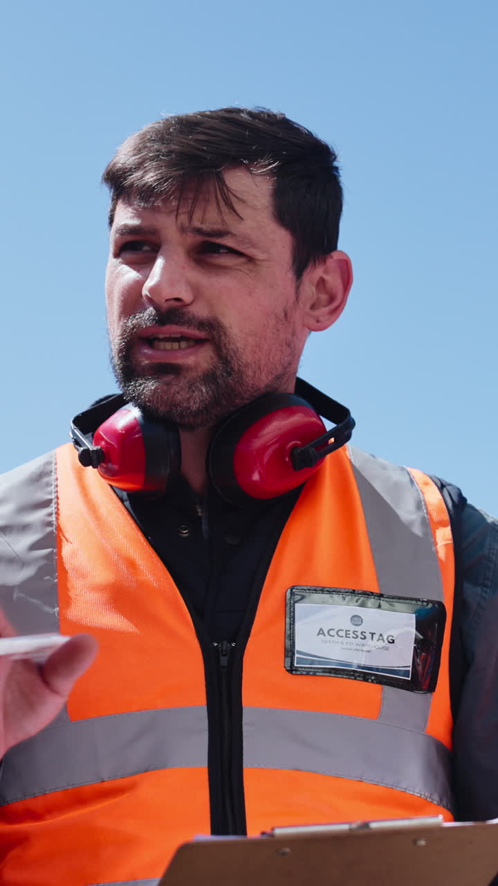 Hombre con chaleco de alta visibilidad hablando y gesticulando en una obra de construcción.