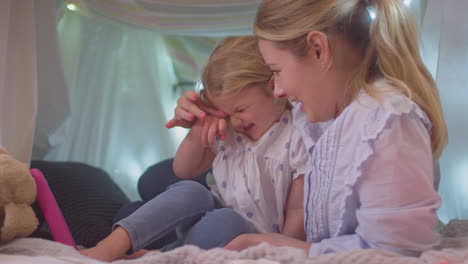 mother and young daughter with digital tablet in homemade camp in child's bedroom at home - shot in slow motion