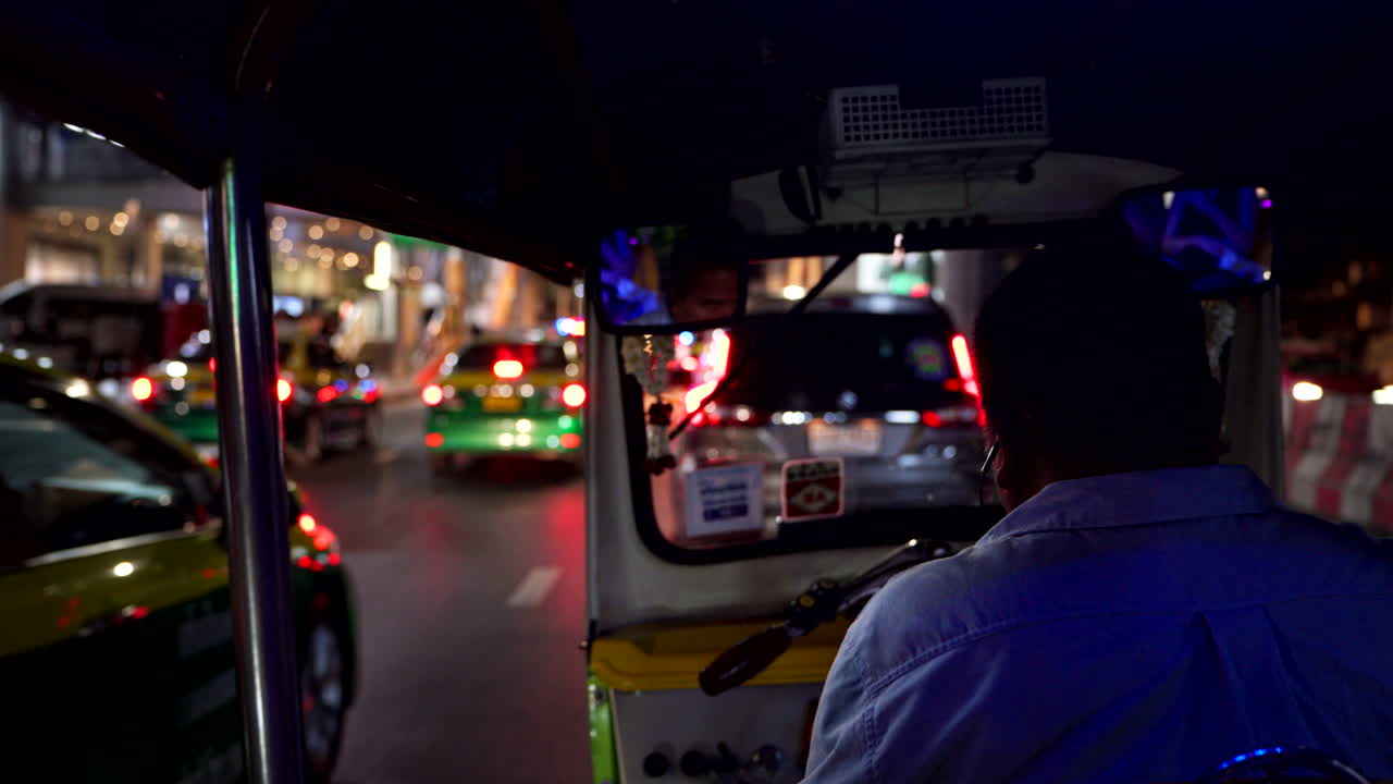 Tuk tuk rides through the bustling streets of Bangkok at night, neon lights illuminating the vibrant city atmosphere, POV of passenger in crowded road