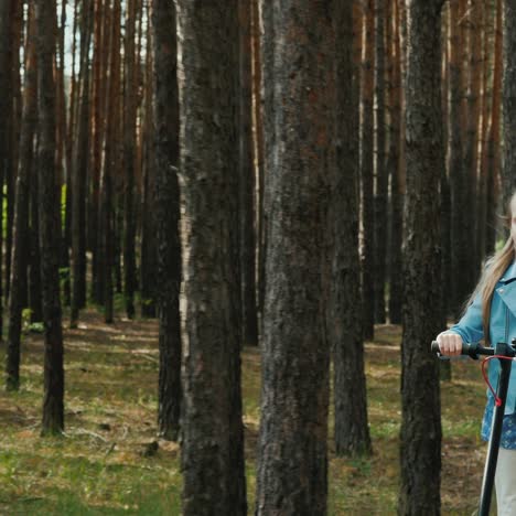 Girl-Rides-Electric-Scooter-On-Road-In-Park-With-Tall-Trees