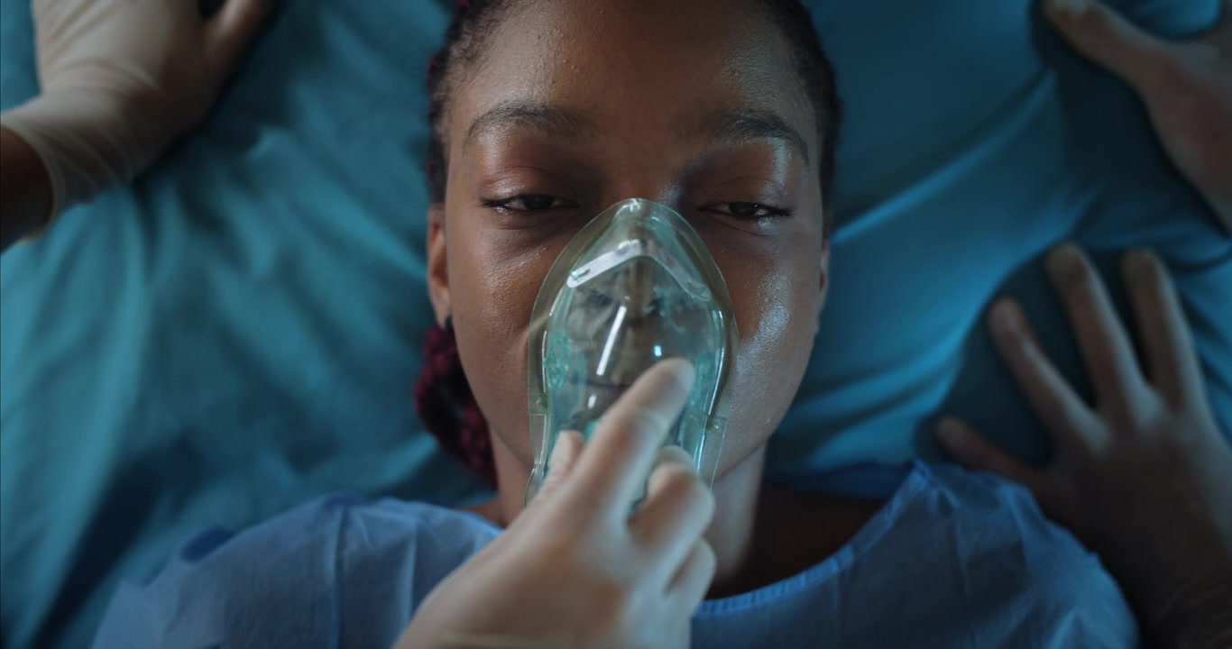 Primo piano di giovane donna afroamericana con maschera d'ossigeno in ospedale