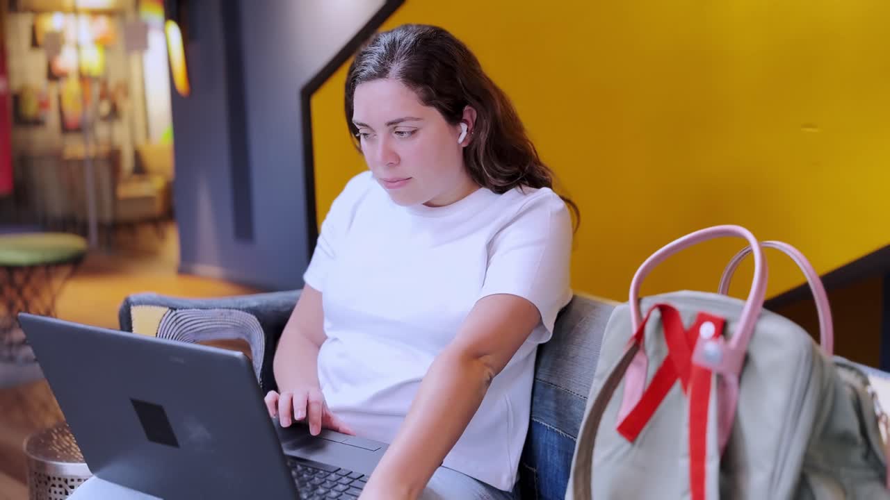 Joven estudiante tecleando en un portátil en un espacio de coworking