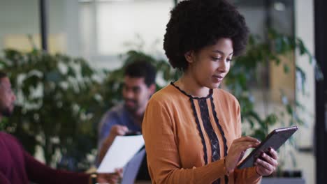 Diverse-business-people-sitting-using-laptops-going-through-paperwork-in-office