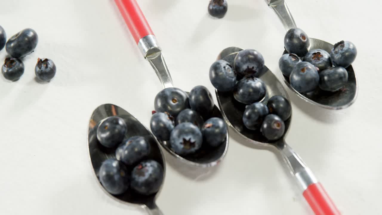 Blueberries in spoon placed on white surface 4K 4k