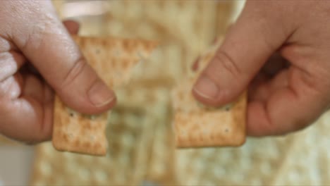 close up of female hands breaking a cracker in half