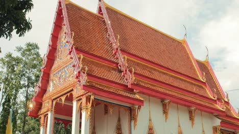 buddhist thai temple with red rooftop and golden decoration in thailand