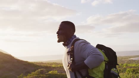 african american man with backpack trying to hitch a lift while walking on the road