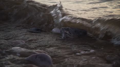 grey sea waves forming and collapsing on big wet rock at shore. slow motion
