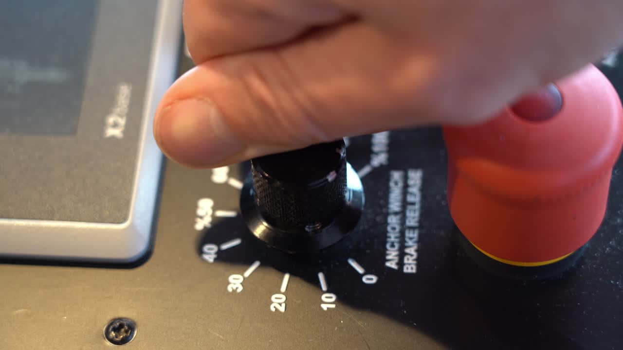 el capitán del barco gira la perilla de liberación del ancla de emergencia en el panel de control