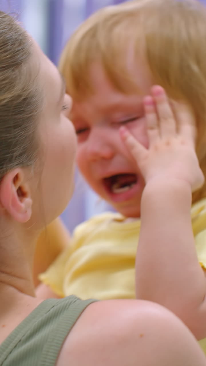 задний вид матери, которая держит и пытается утешить свою плачущую дочь, как в тренажерном зале, захватывая нежный момент материнской заботы и эмоциональной поддержки