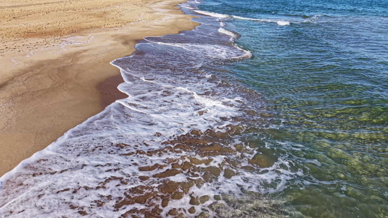 Interplay dinamico di terra e mare sulla costa tranquilla durante un soleggiato pomeriggio in riva al mare