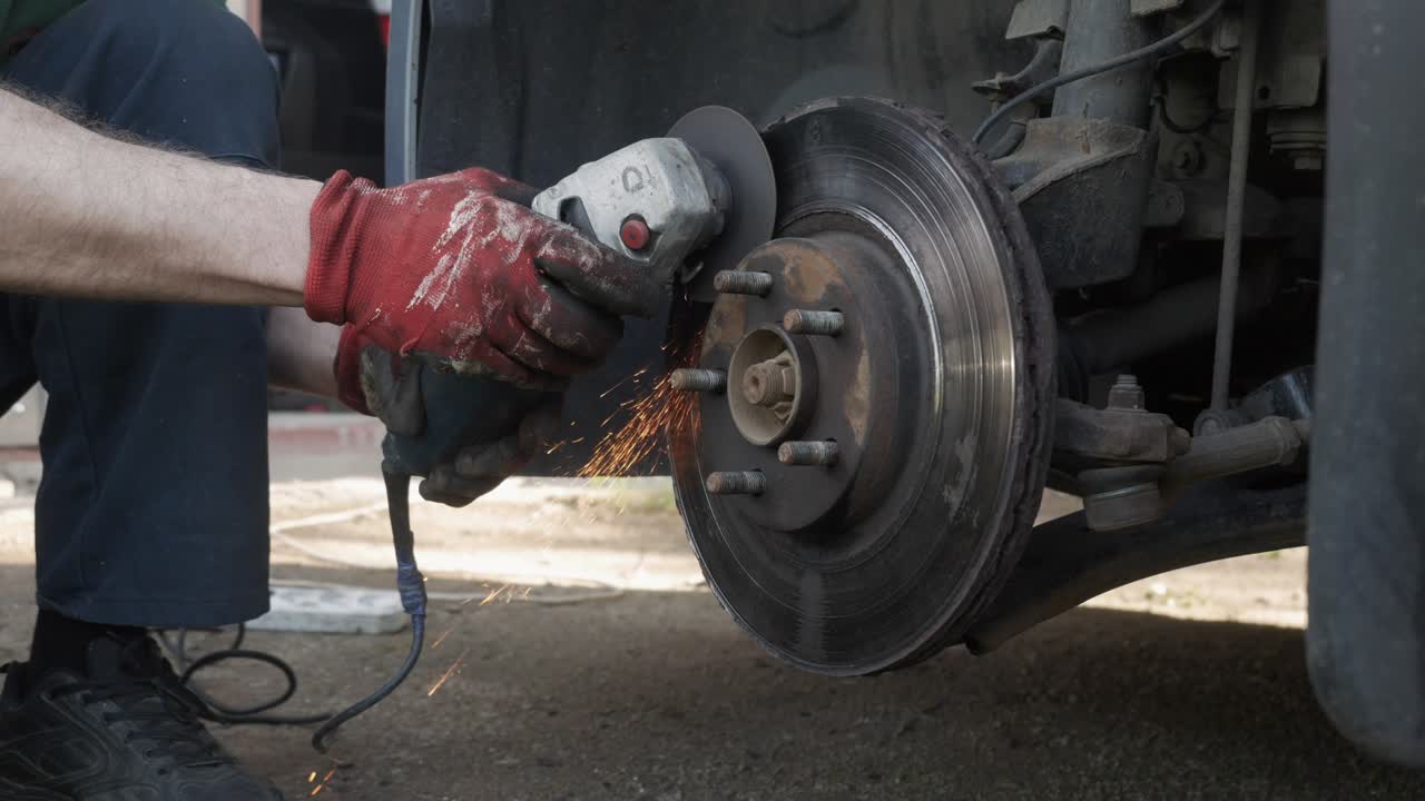 el mecánico corta la rueda del coche con una molienda