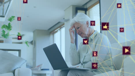 animación de la red de conexiones con iconos sobre una mujer caucásica anciana preocupada usando una computadora portátil