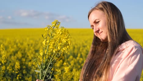 attractive blonde of european appearance admires a bouquet of rapeseed flowers attractive blonde of european appearance admires a bouquet of rapeseed flowers rapeseed field and blue sky woman sniffs a bouquet of flowers