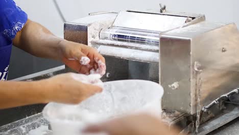 person sifting flour through industrial equipment