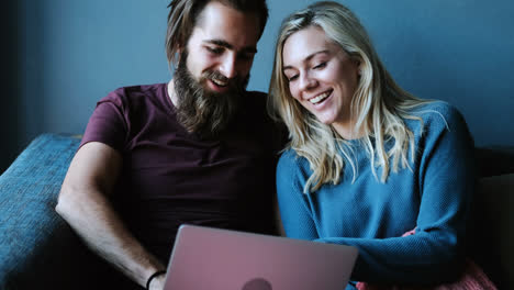 Couple-using-laptop-on-sofa-at-home-4k